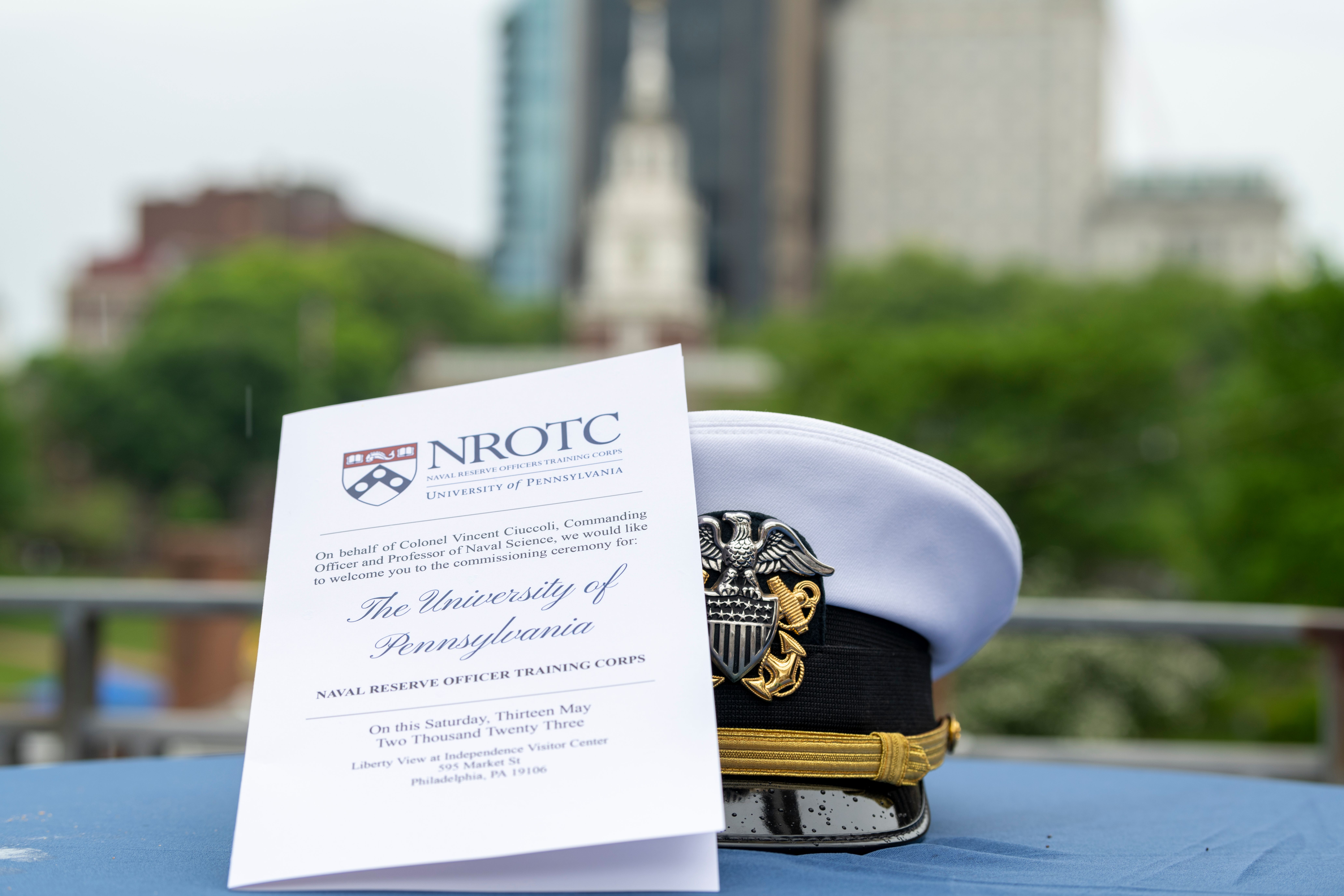 An Ensign cover and program pamphlet lay on a balcony table with Independence Hall in the background